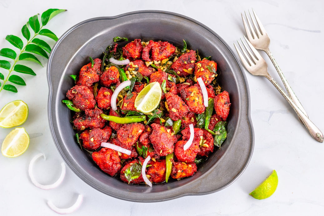 Chicken 65, Spicy Deep Fried Indian Chicken with Curry Leaves and Lemon on White Background Directly Above Photo